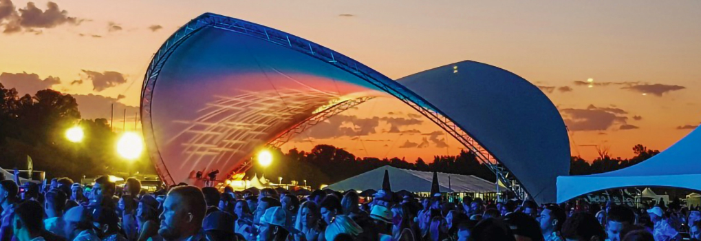 Large clear-span event tent by Tentnology hosting an outdoor festival and live concert.