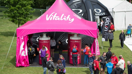 Outdoor trade show booth under a Tentnology custom logo tent with full-color branding on canopy.