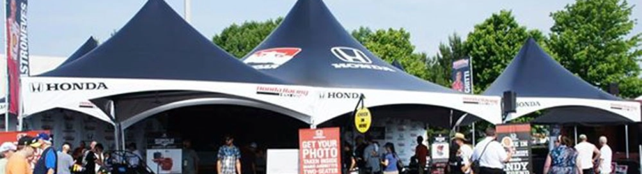 Custom branded event tent with commercial logos, large multi-peak canopy structure used for outdoor events and experiential marketing.