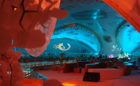 Illuminated event tent interior with blue and red lighting and lounge seating